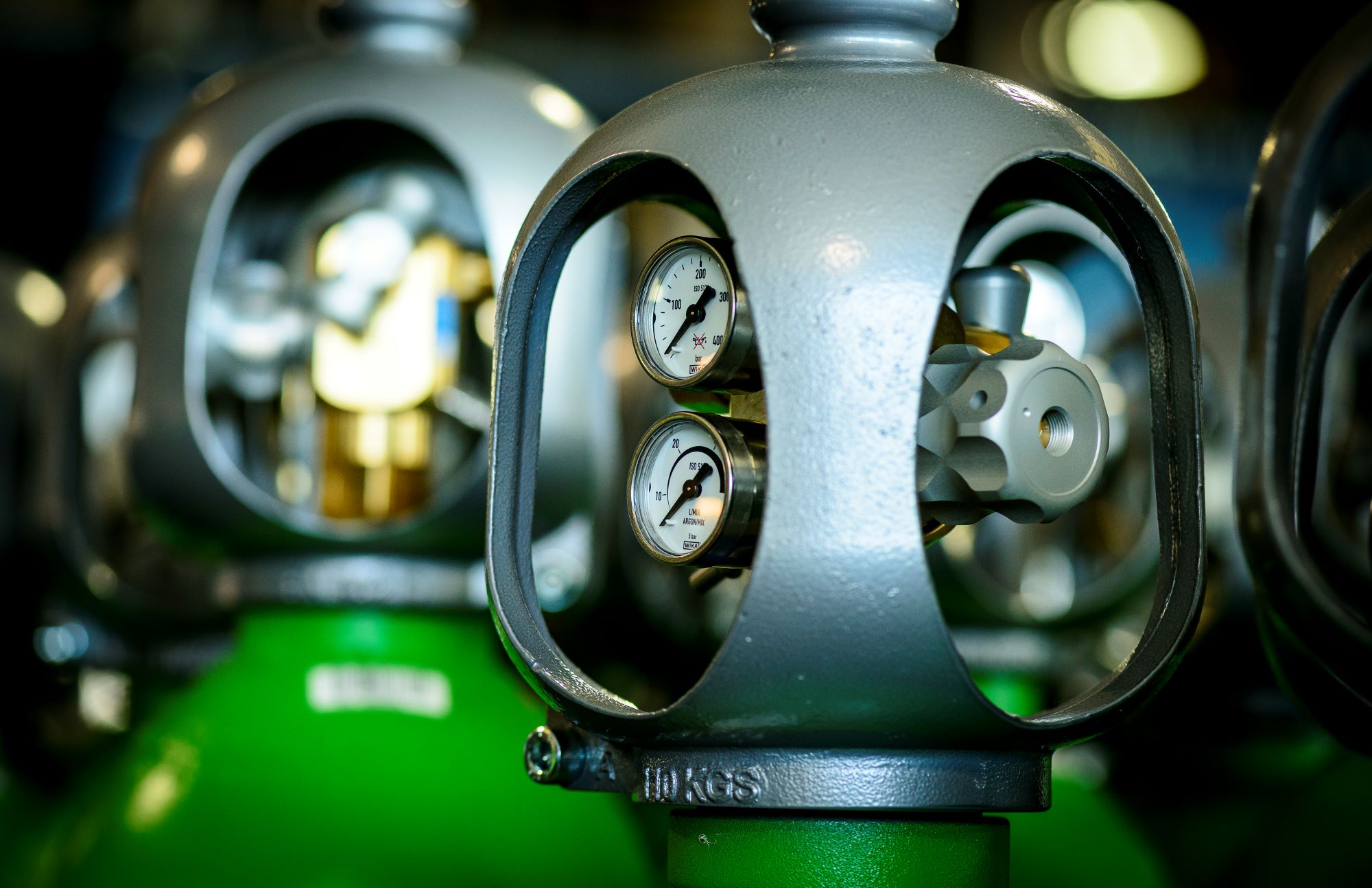 Close-up of industrial gas cylinders fitted with pressure gauges and valve assemblies.